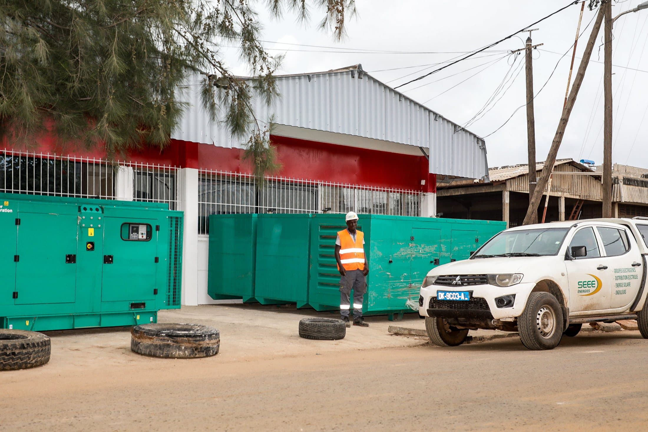 Groupes Cummins turquoise alignés devant l'atelier, un pick-up SEEE et un technicien