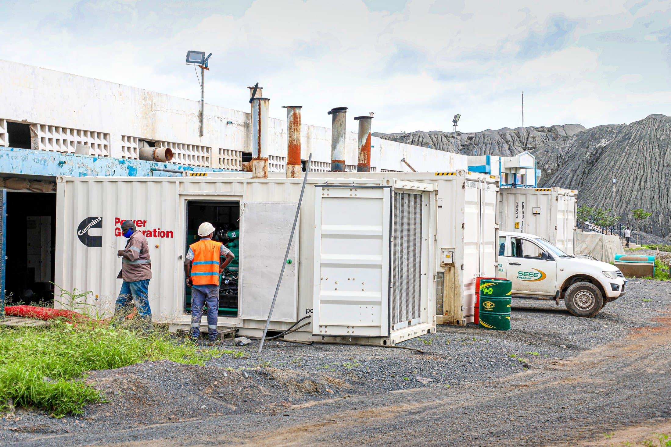 Groupes Cummins en conteneur loués sur un site minier, techniciens en gilet orange